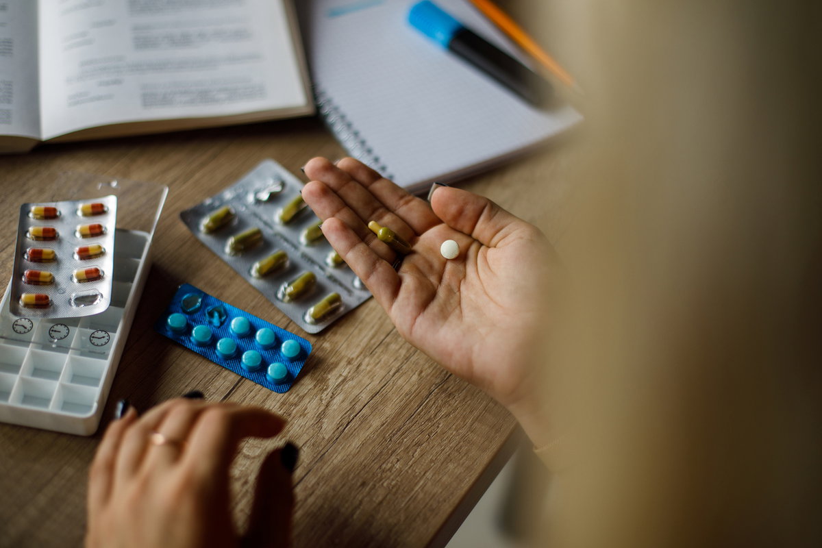 Frau hat verschiedene Filmtabletten vor sich liegen