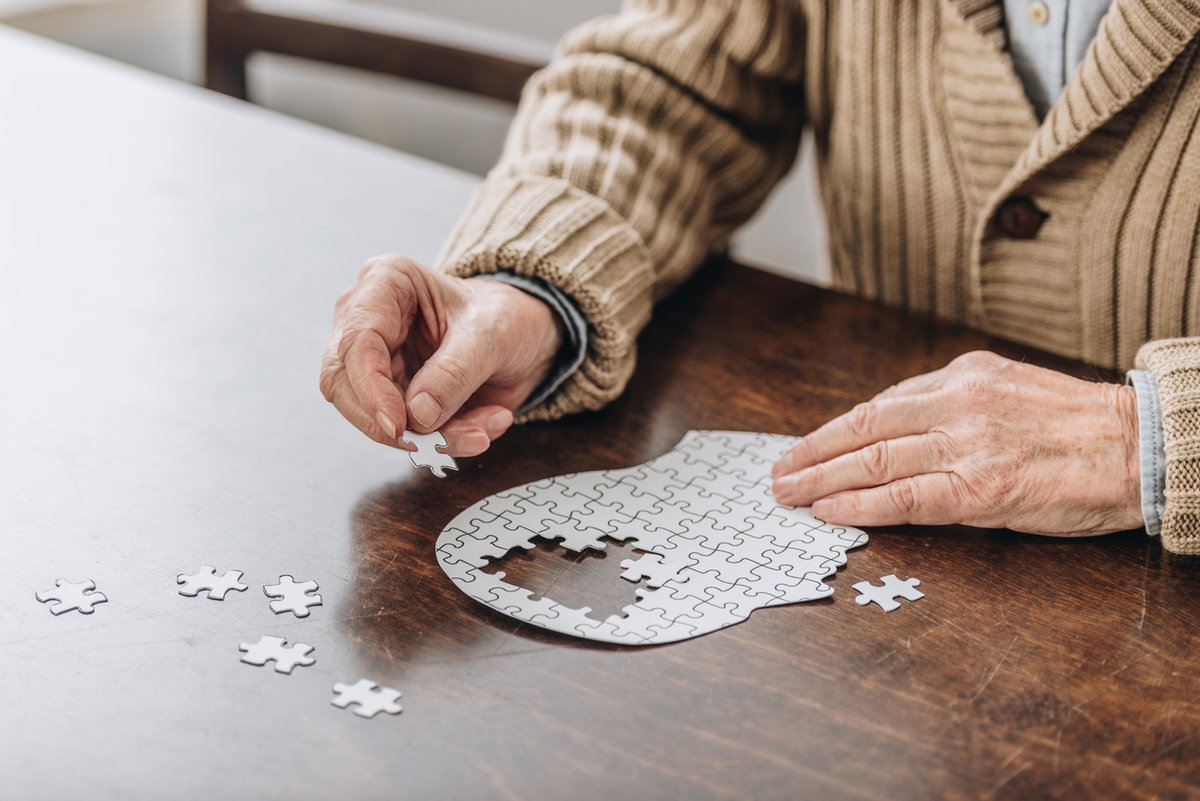 Alter Mann puzzelt auf Tisch