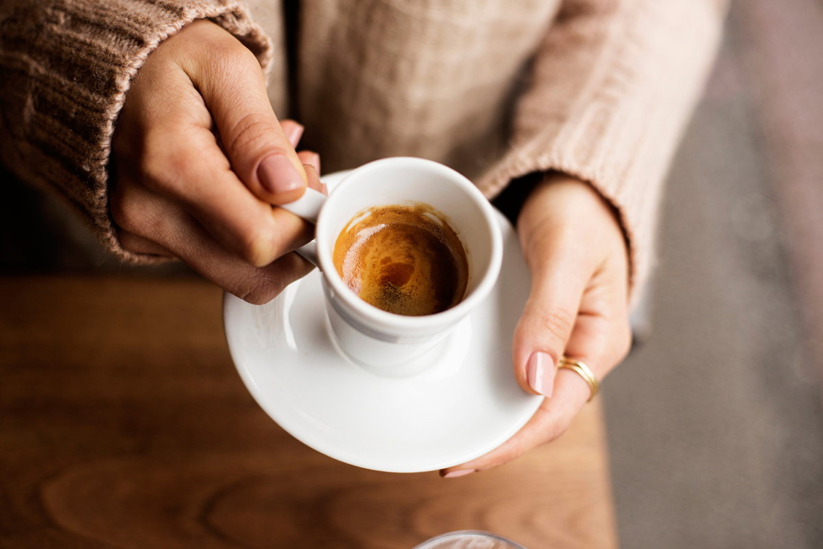 Frau hält Tasse mit Espresso in den Händen