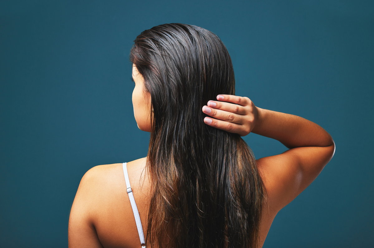 Rückenansicht einer Frau, die ihre Haare mit den Fingern durchkämmt