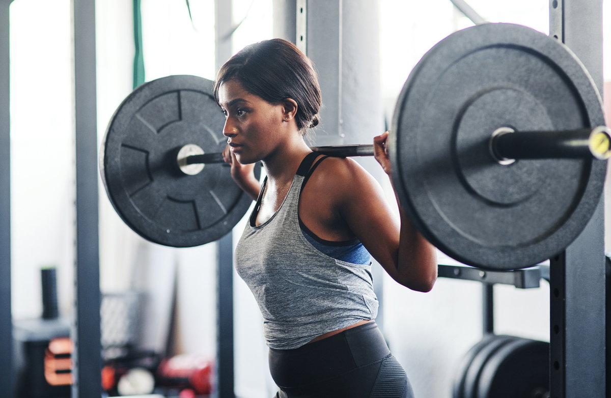 Frau macht Back-Squats im Squat-Rack