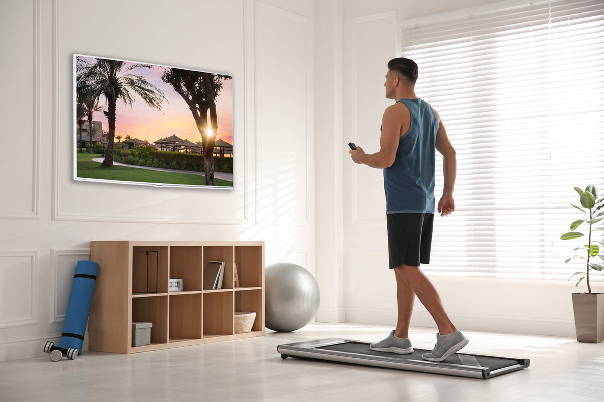 Mann geht auf kleinem Laufband im Wohnzimmer spazieren