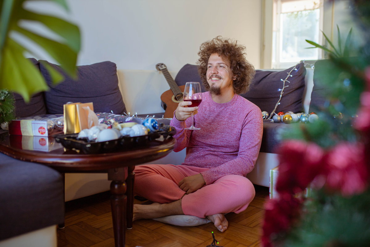Mann sitzt mit Weinglas alleine vor dem Fernseher