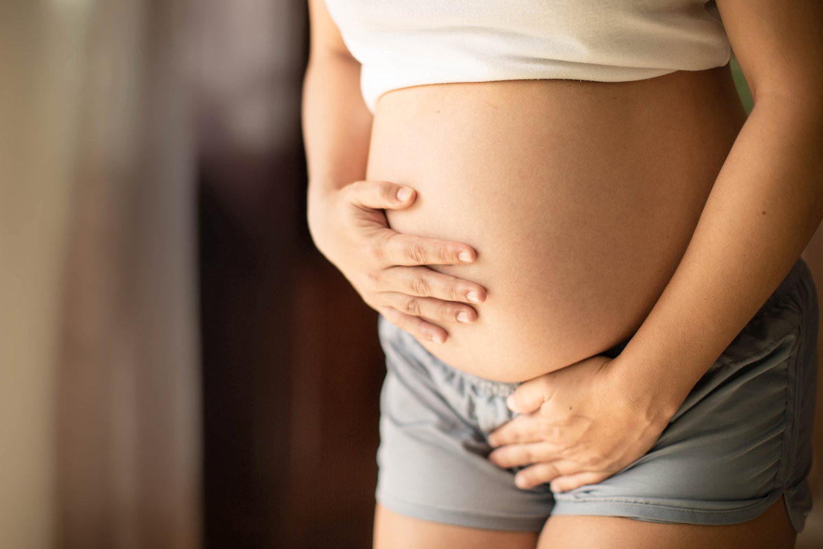 Schwangere Frau hält sich den Bauch