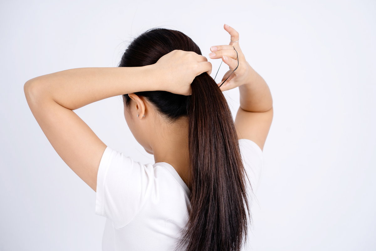Frau bindet Haare zusammen