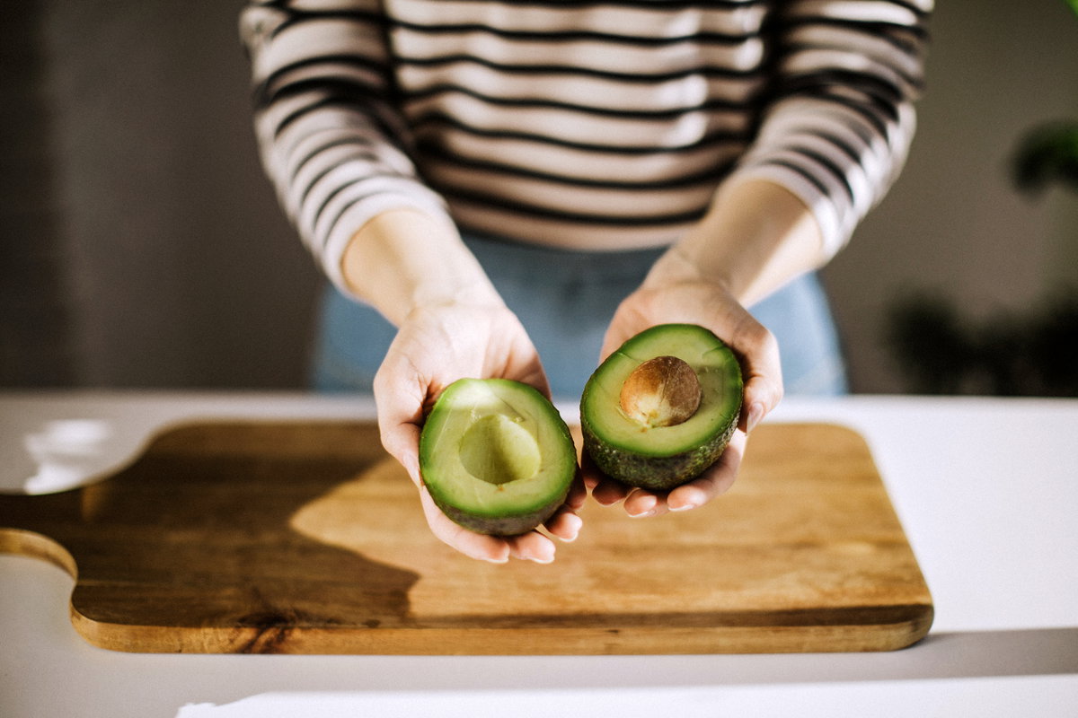 Frau hält Avocado in der Hand