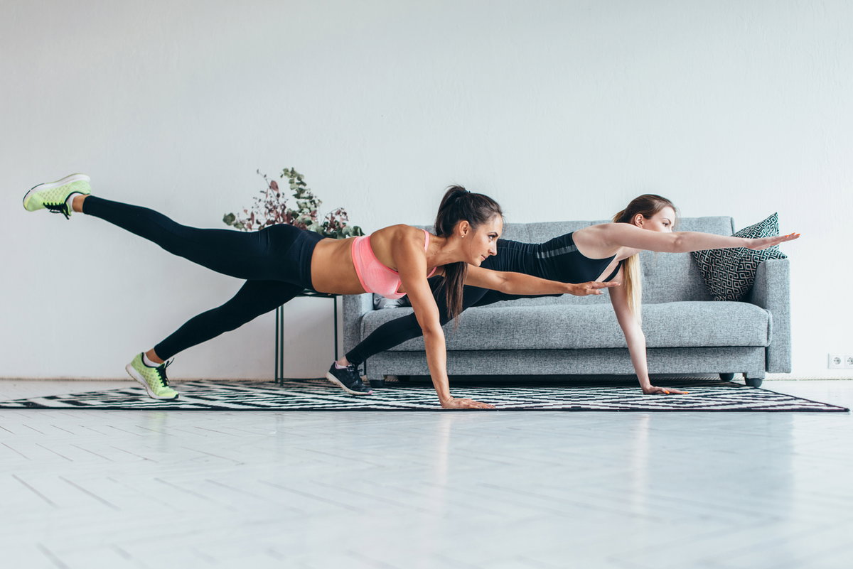 Frauen machen Planks mit Arm- und Beinheber in Wohnzimmer
