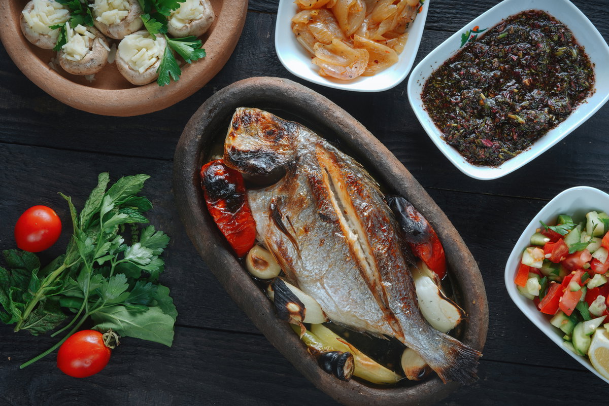 Gegrillter Fisch mit Salat und mediterranen Beilagen