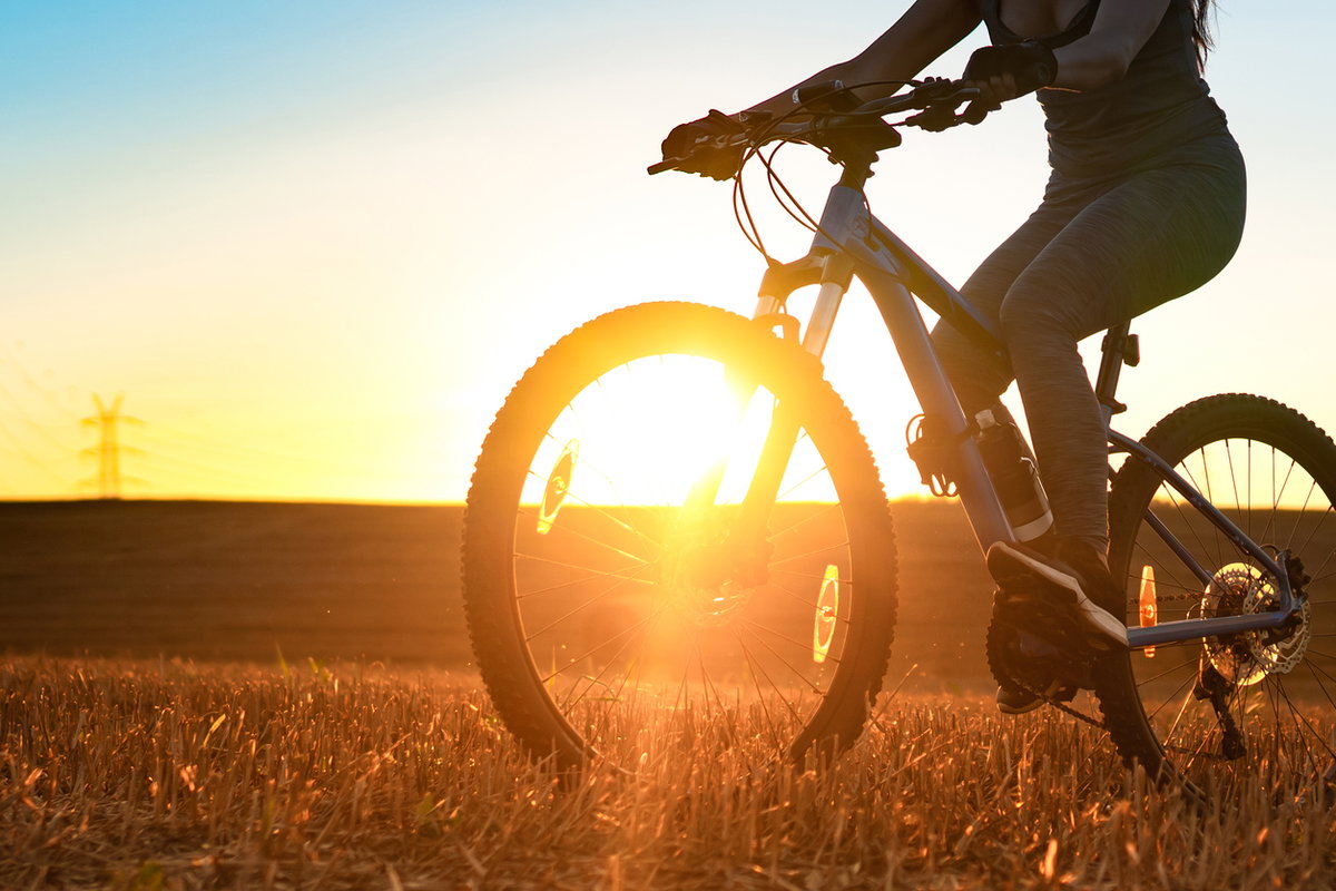 Frau fährt in der Abendsonne auf dem Fahrrad