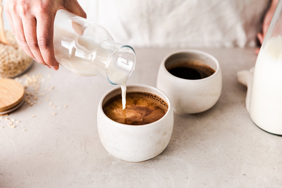 Hafermilch wird in den Kaffee gegossen
