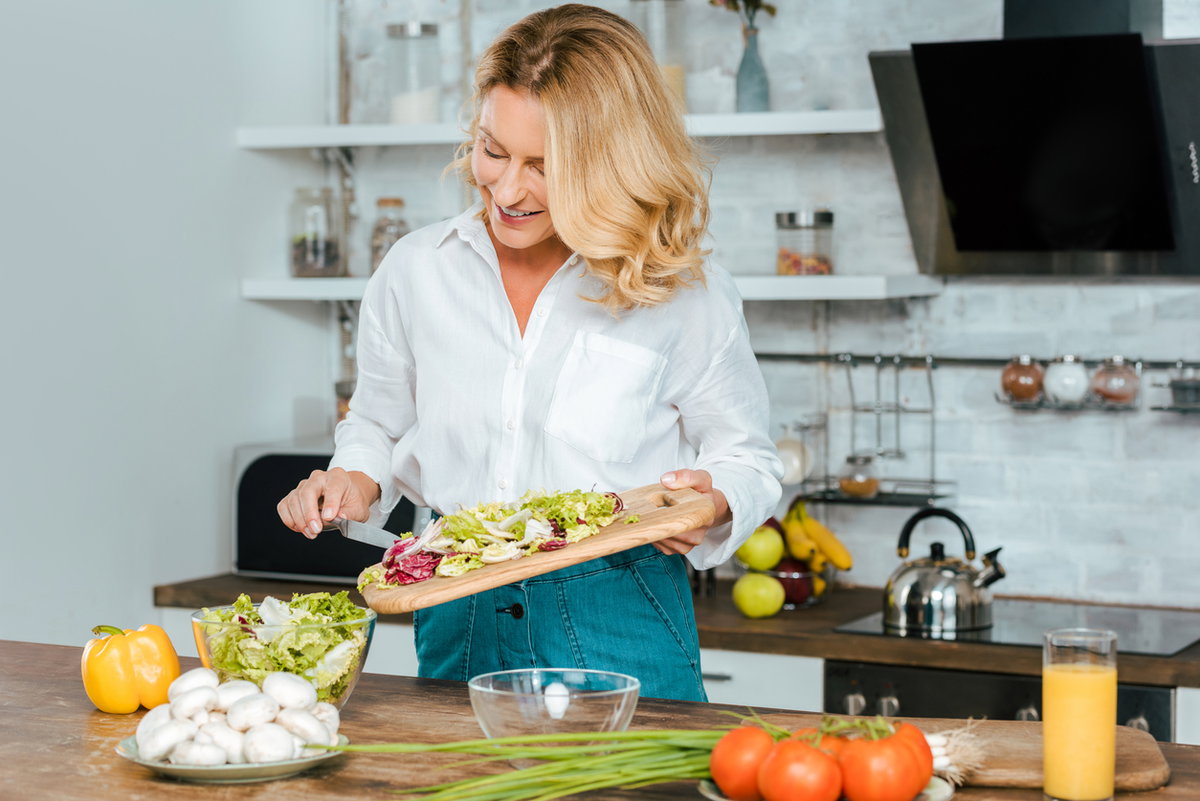 Frau schneidet Salat selbst