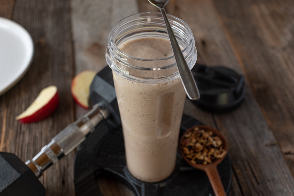 Proteinshae und Hantel auf Holztisch