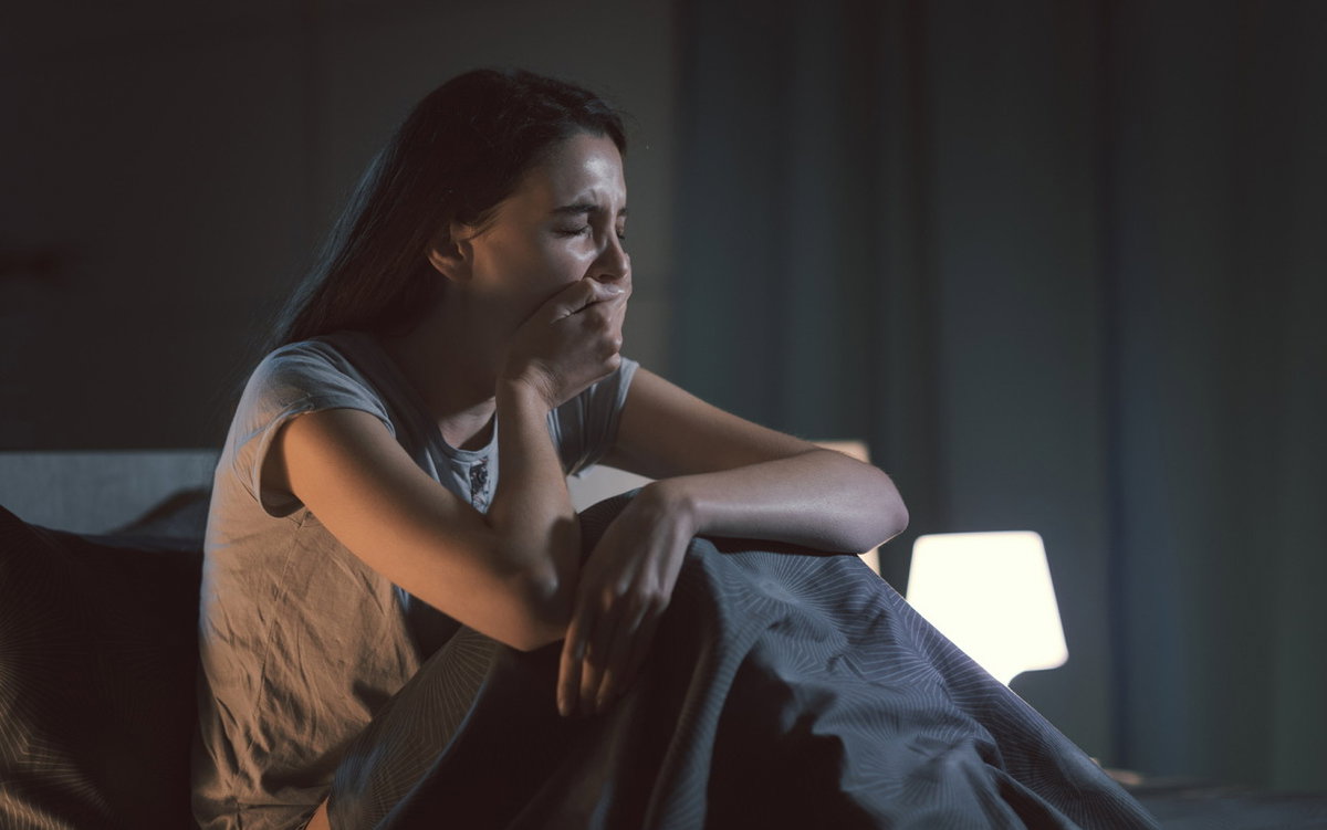 Müde Frau gähnt mitten in der Nacht im Bett