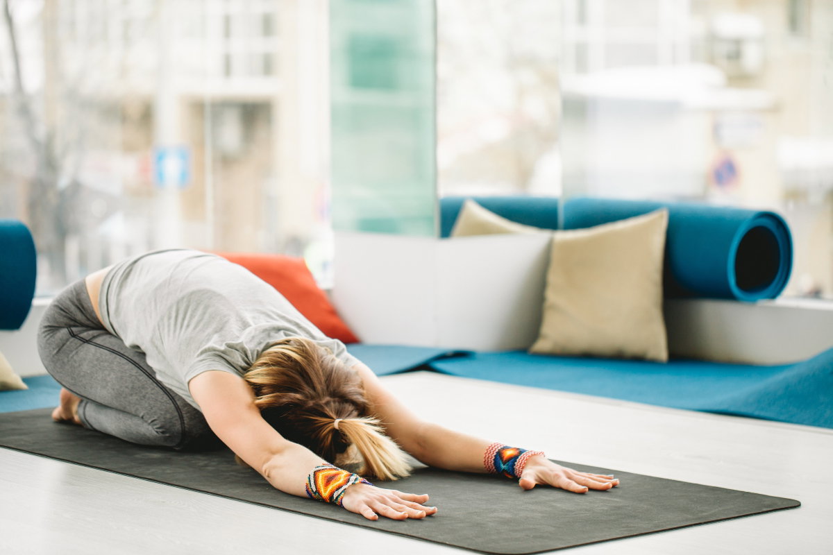 Frau macht Dehnübung auf Yoga-Matte