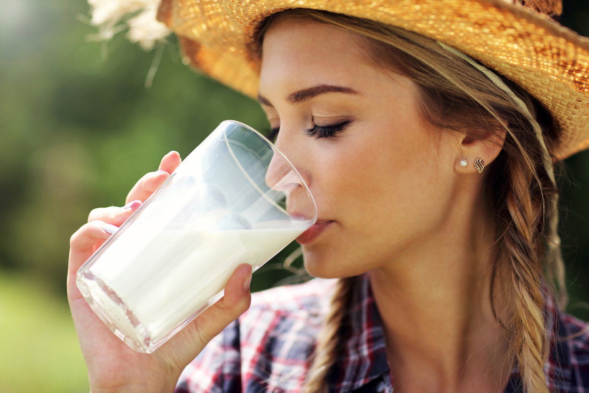 Frau mit Hut trinkt Milch aus Glas