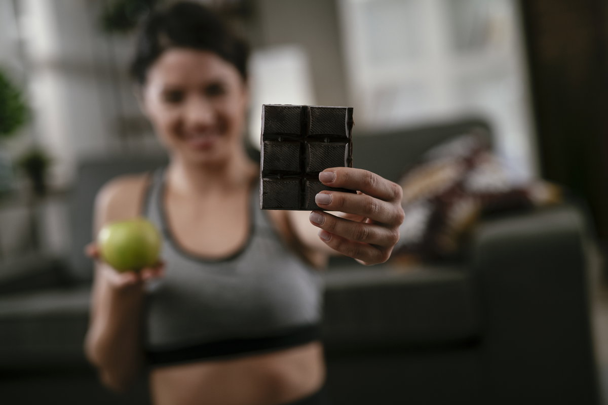 Frau beim Sport isst Schokolade