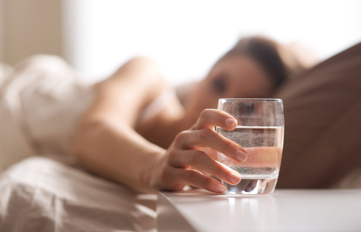 Frau trinkt Wasser im Bett