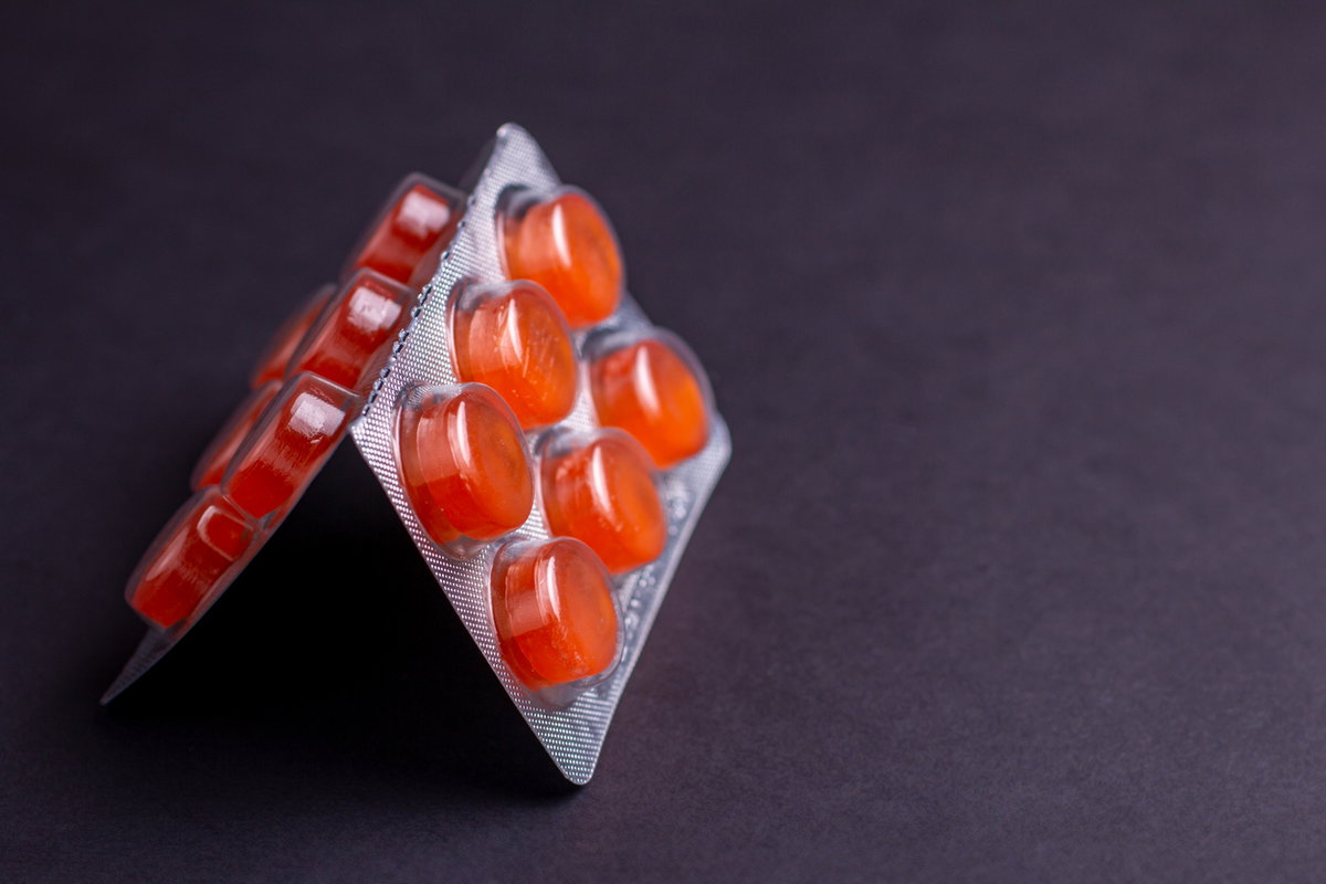 Halsschmerztabletten auf schwarzem Untergrund