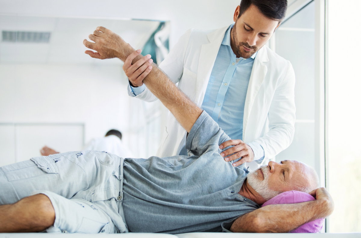 Arzt untersucht Schulter eines Patienten