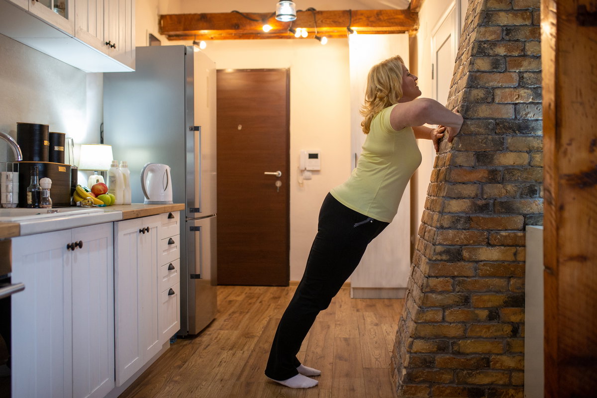 Frau macht Push ups gegen Wand