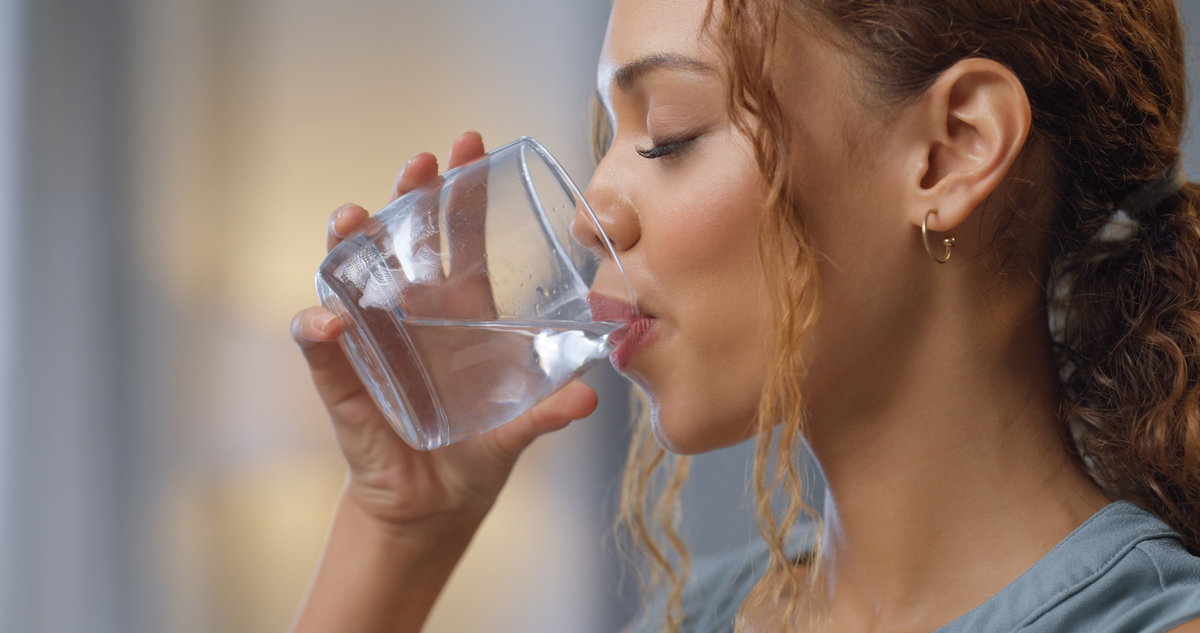 Frau trinkt Wasserglas.