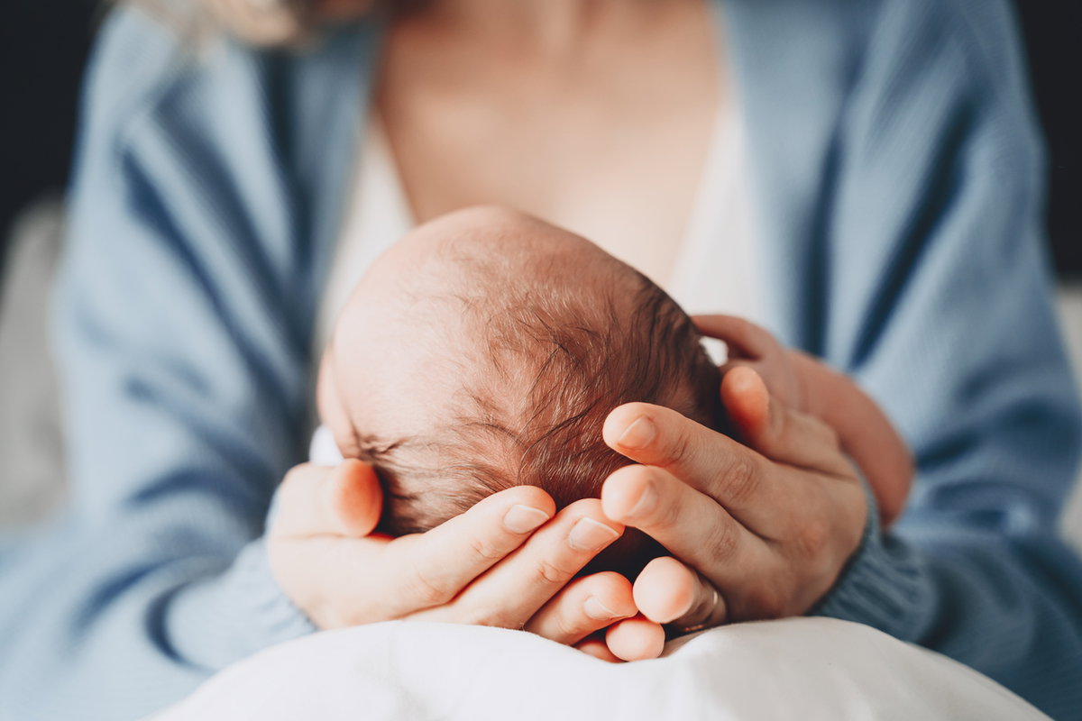 Mutter hält Neugeborenes in der Hand