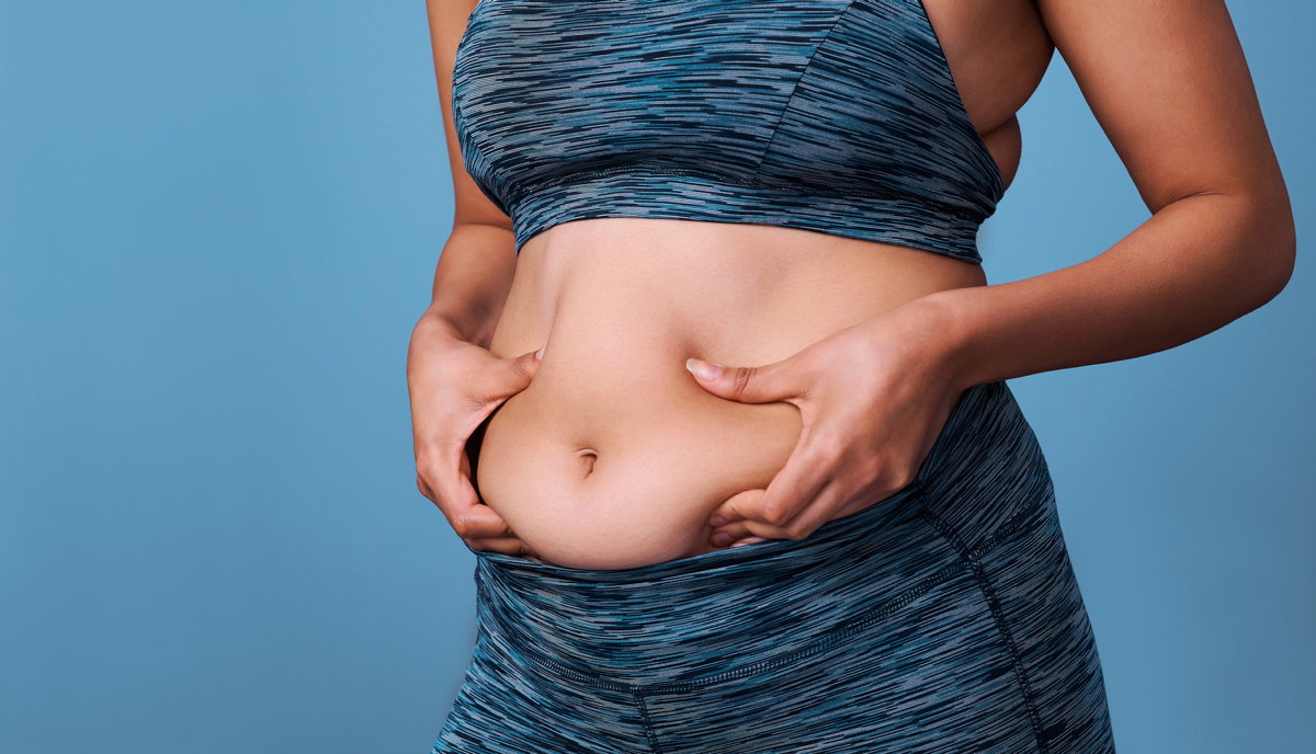 Frau in Sportsachen hält sich Bauch