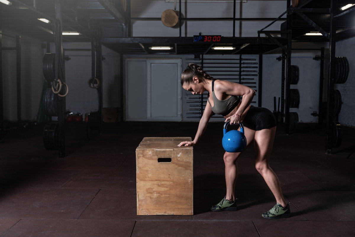Frau mit Kettlebell macht einarmiges Rudern