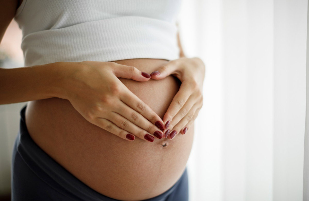 Schwangere Frau hält sich den Bauch