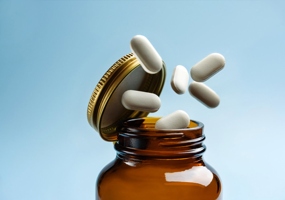 Tabletten fallen aus einer Glasflasche