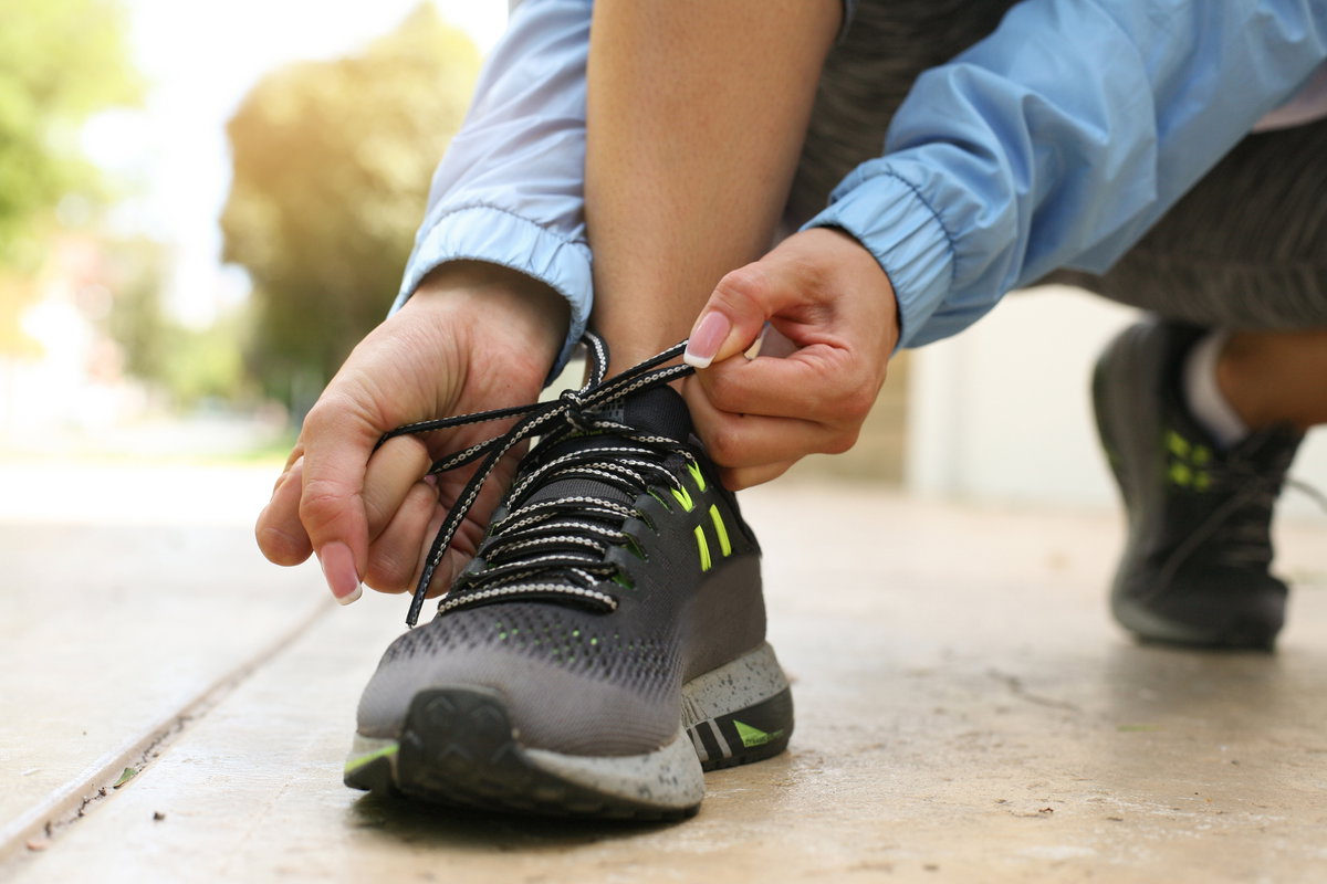 Frau bindet sich Sportschuhe zu