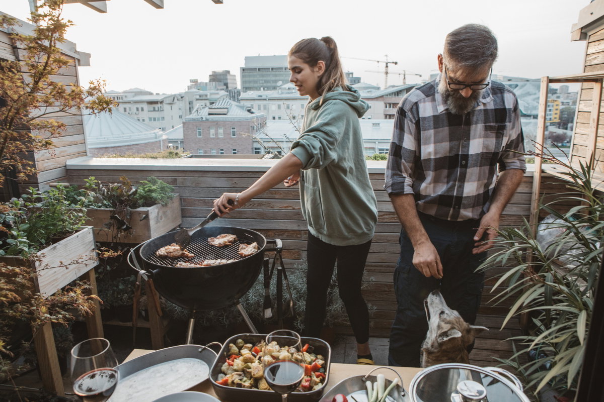 Mann und Frau grillen auf Balkon