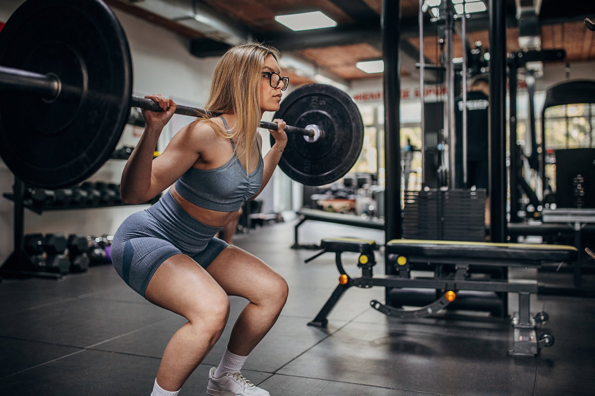 Frau macht Squats im Fitnessstudio