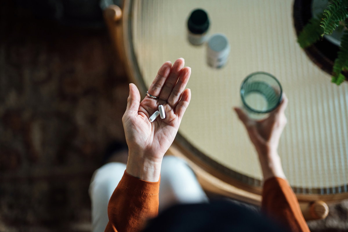 Frau hält Vitaminpräparate in der Hand