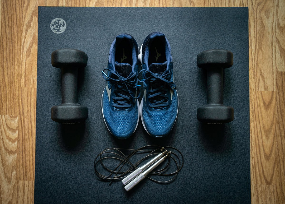 Sportschuhe und Hanteln auf Yoga-Matte