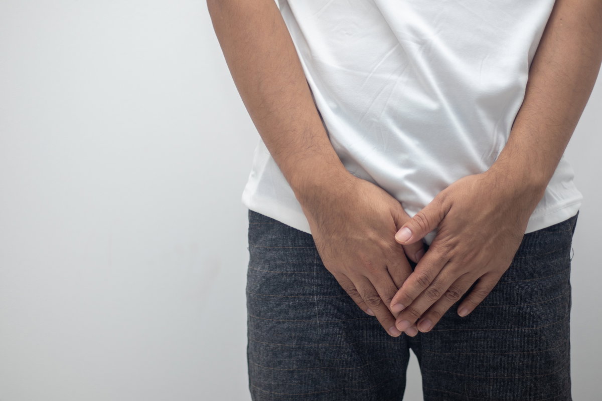 Mann hält sich die Hände vor den Intimbereich