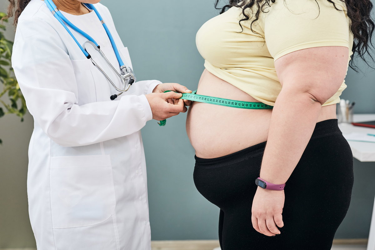Ärztin misst Bauchumfang einer übergewichtigen Patientin.