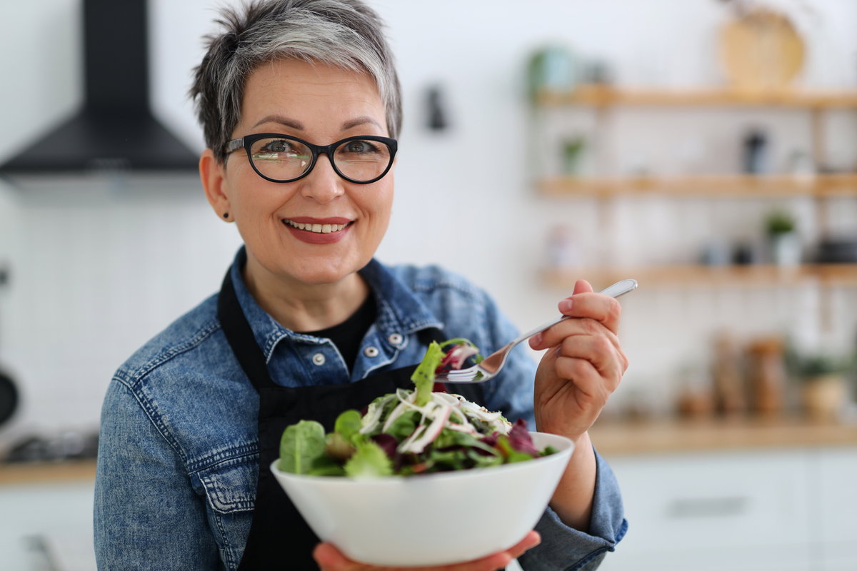 Frau im mittleren Alter isst Salat