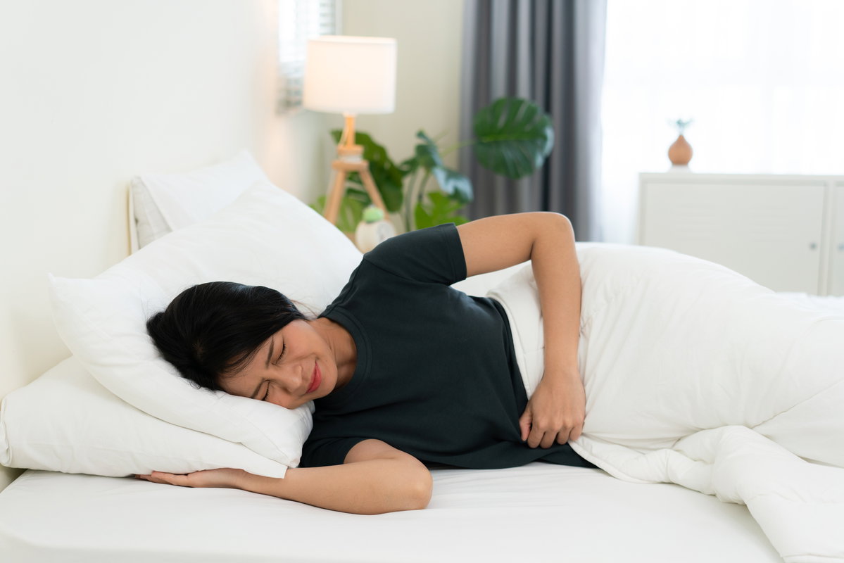 Frau im Bett mit Schmerzen