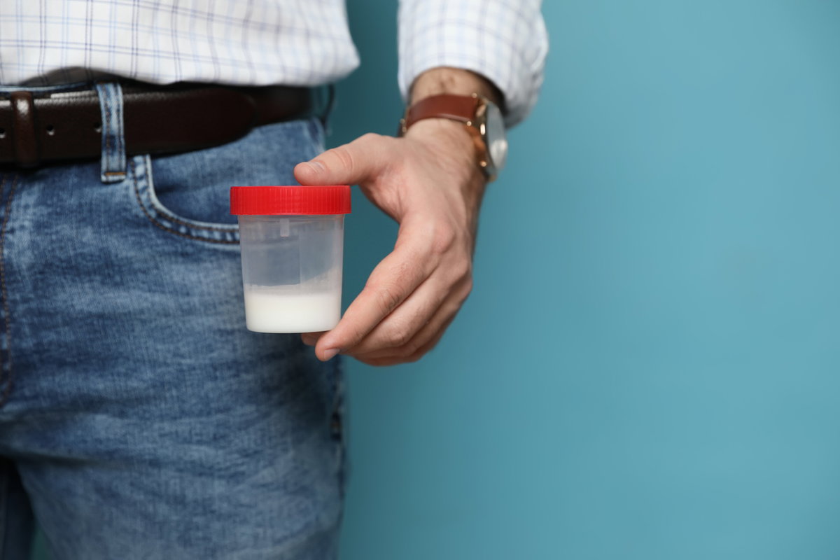 Mann hält Spender-Container mit der Sperma-Farbe weiß