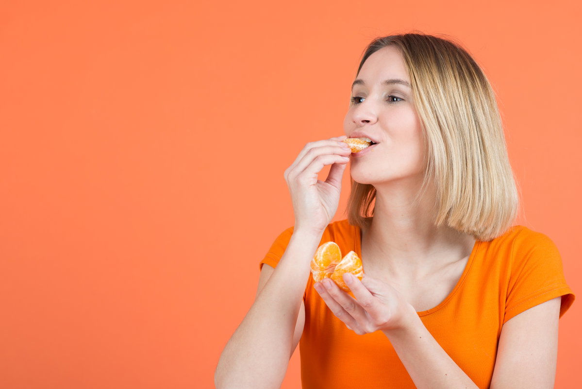 Frau beißt in Mandarine
