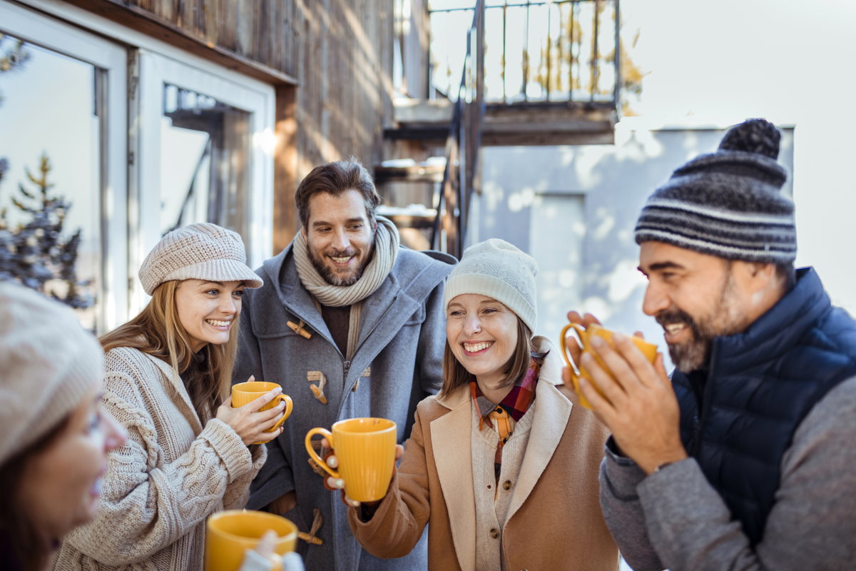 Menschen stehen draußen und trinken gemeinsam Glühwein