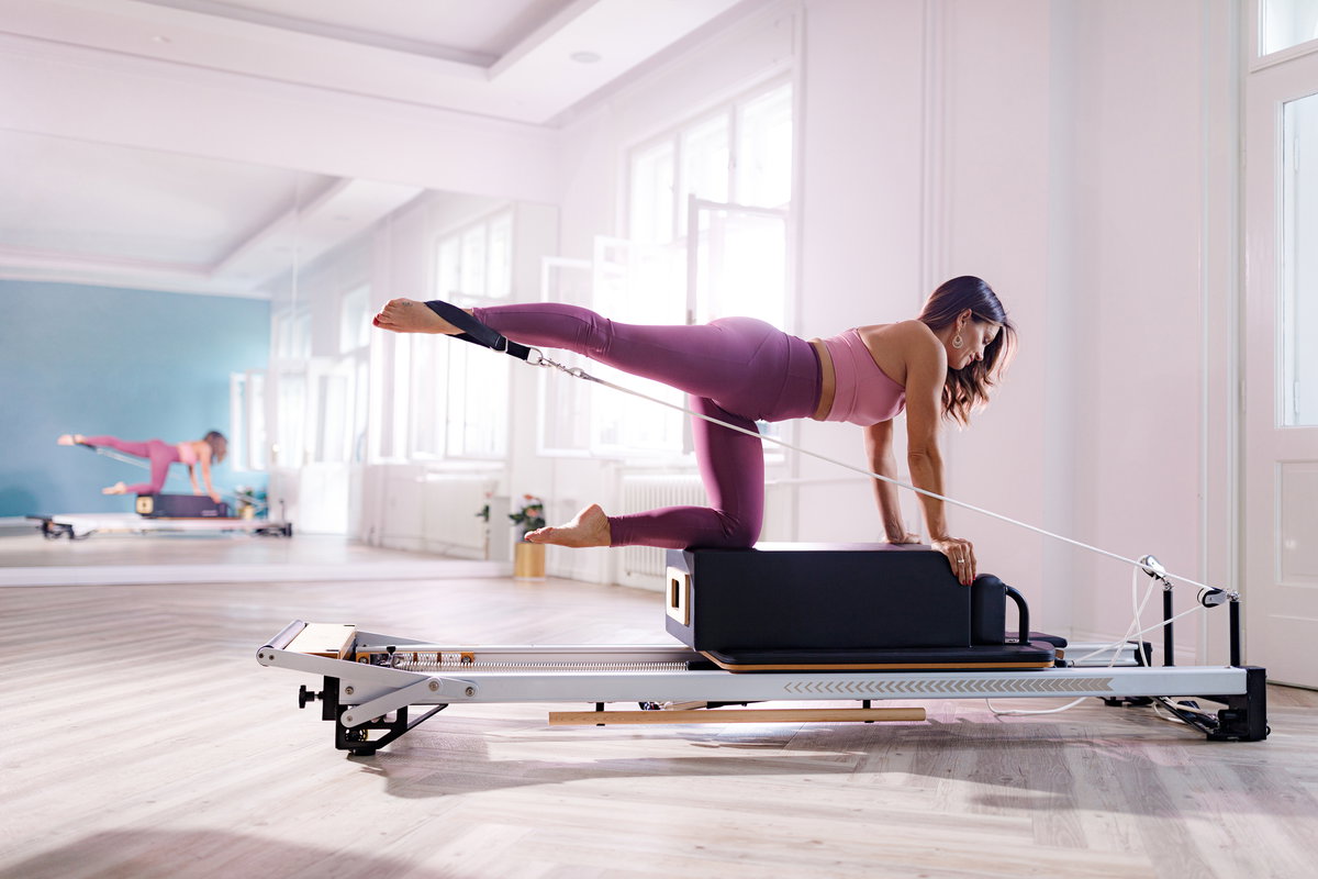 Frau trainiert mit Pilates Reformer