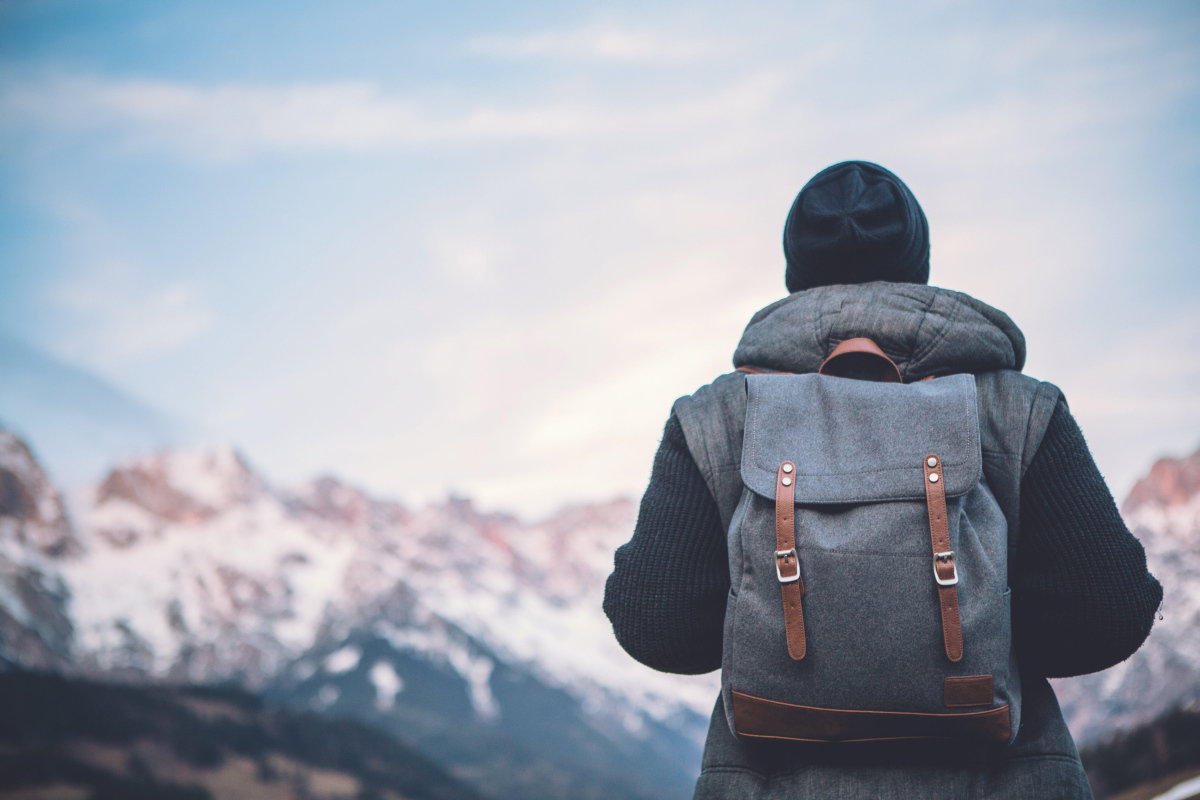 Mann mit Rucksack blickt auf winterliche Berglandschaft