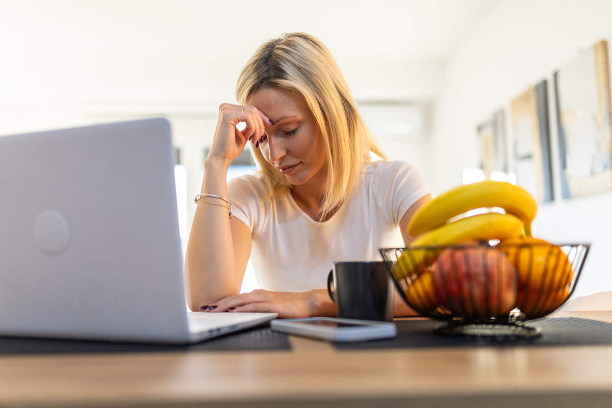 Frau sitzt am Laptop und ist erschöpft