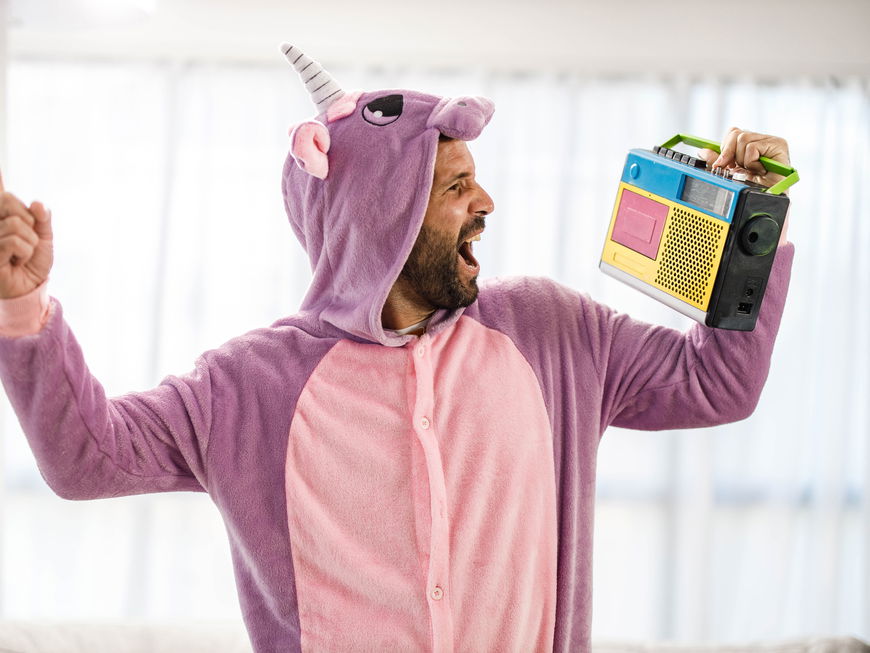 Verspielter Mann im Einhornkostüm singt mit Radiomusik