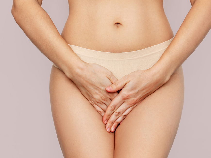 Frau in Unterhose hält die Hände vor ihren Intimbereich