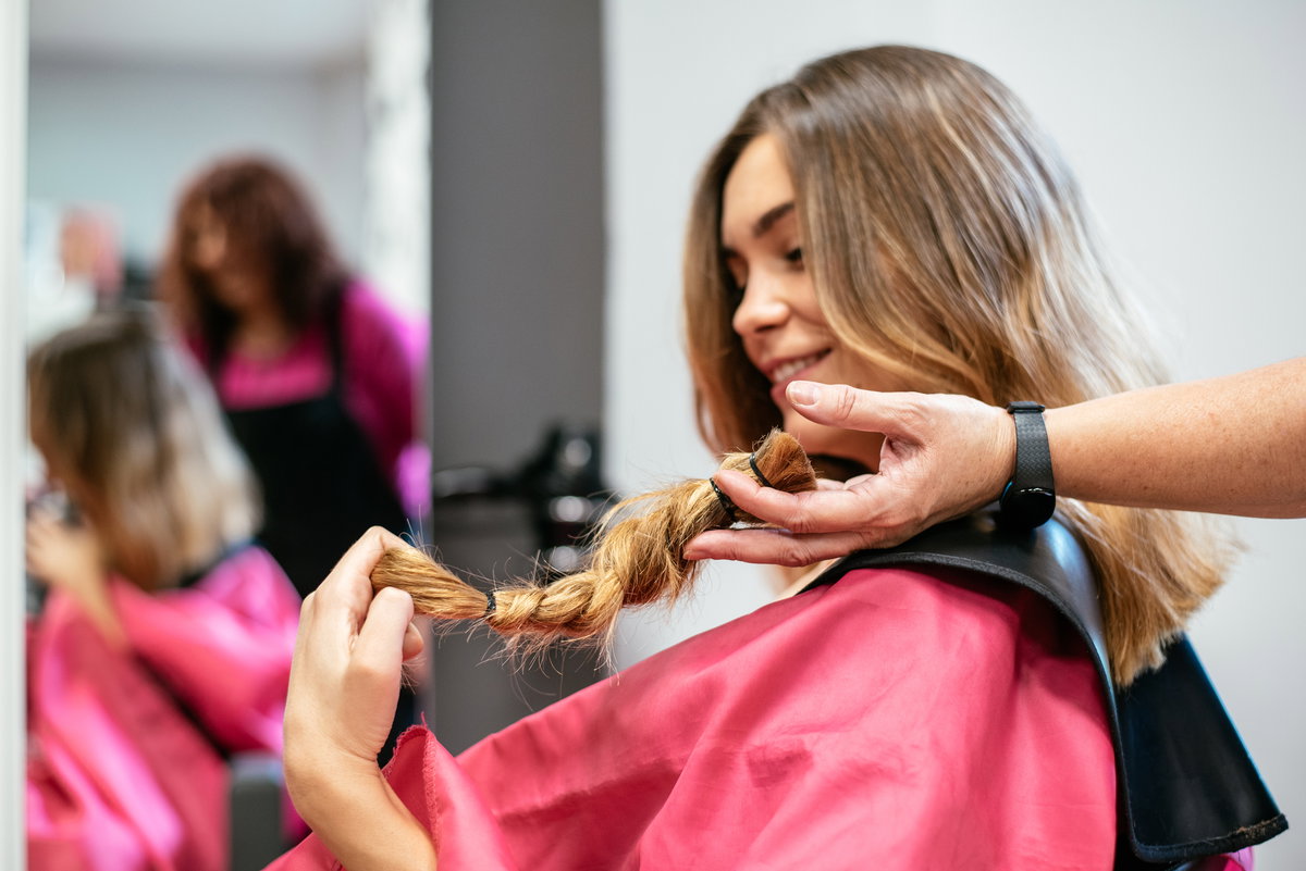 Frau sitzt beim Friseur, um ihre Haare zu spenden