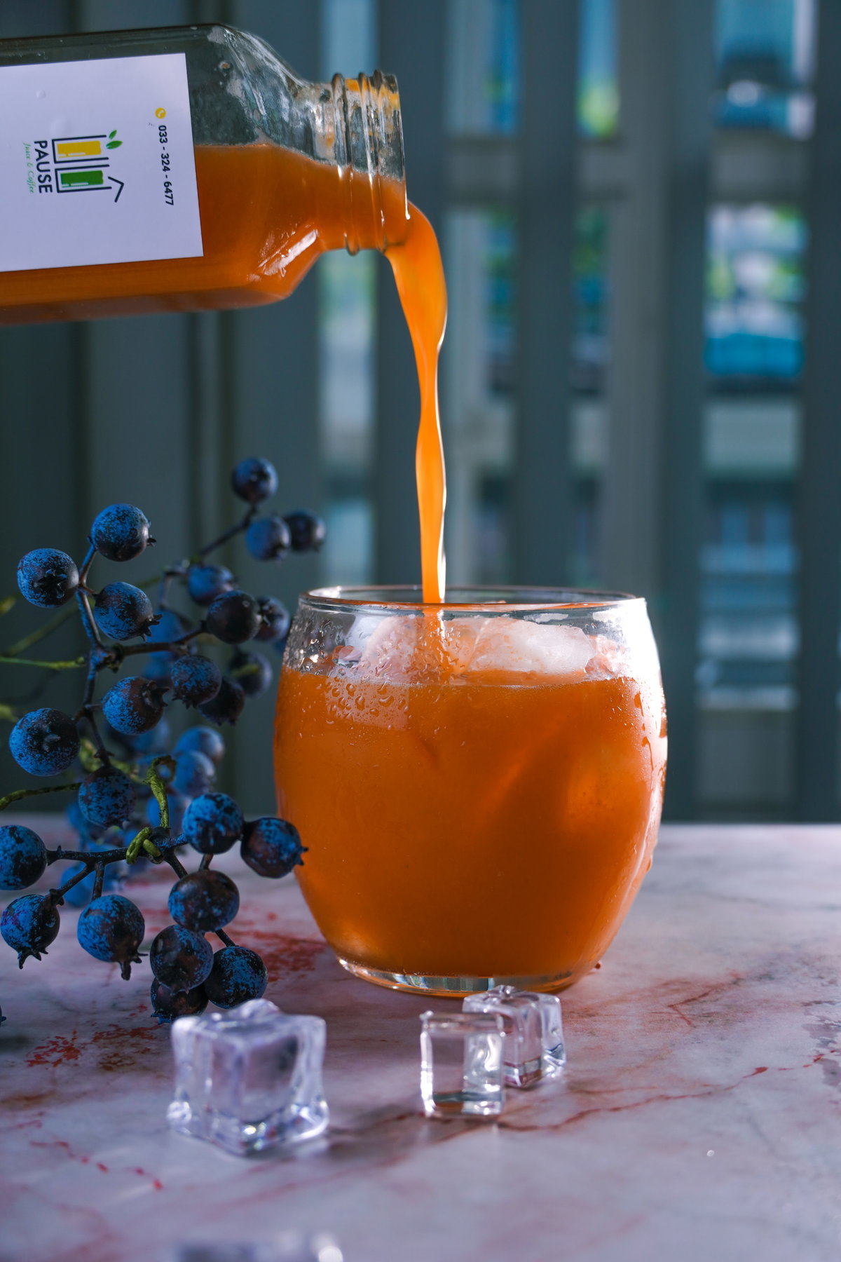 Karottensaft wird in ein Glas mit Eiswürfeln gegossen