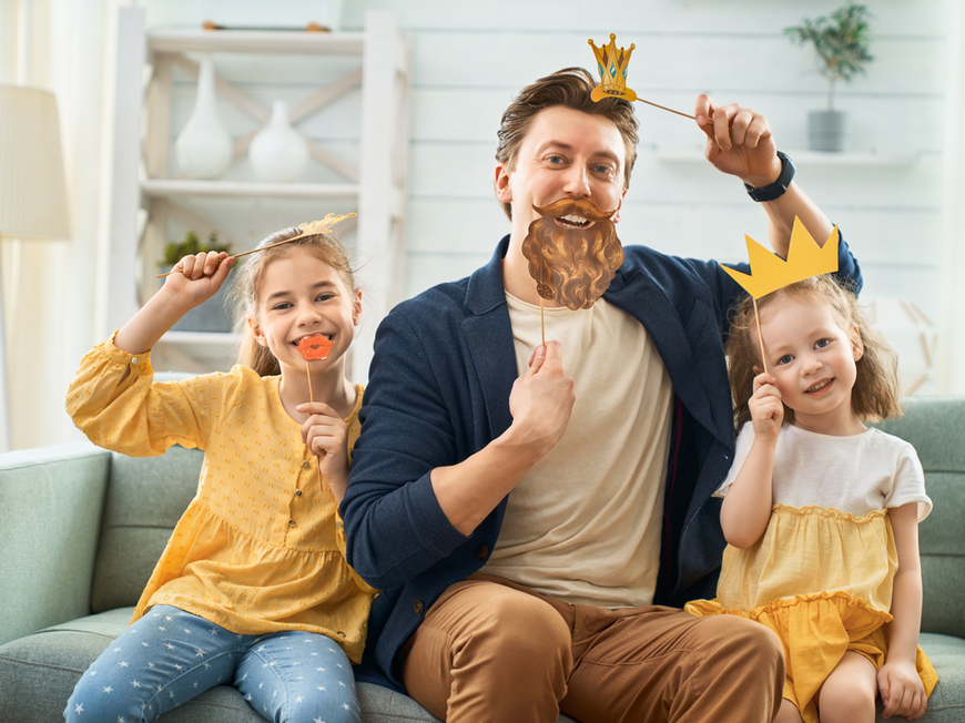 Ein Vater spielt mit seinen Kindern, sie tragen Masken